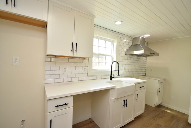 kitchen with white cabinetry, sink, decorative backsplash, and wall chimney range hood