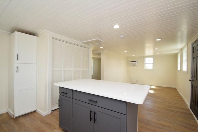 kitchen with a wall mounted AC, a center island, gray cabinets, and light hardwood / wood-style floors