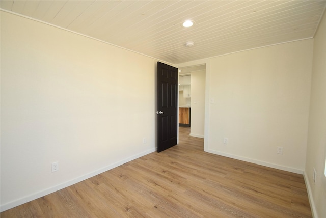 empty room featuring light hardwood / wood-style flooring and wooden ceiling