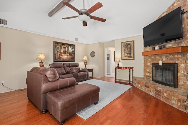 living room with lofted ceiling with beams, wood-type flooring, a brick fireplace, and ceiling fan