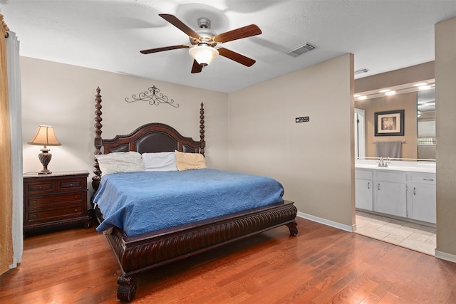 bedroom featuring hardwood / wood-style flooring, ceiling fan, sink, and ensuite bath