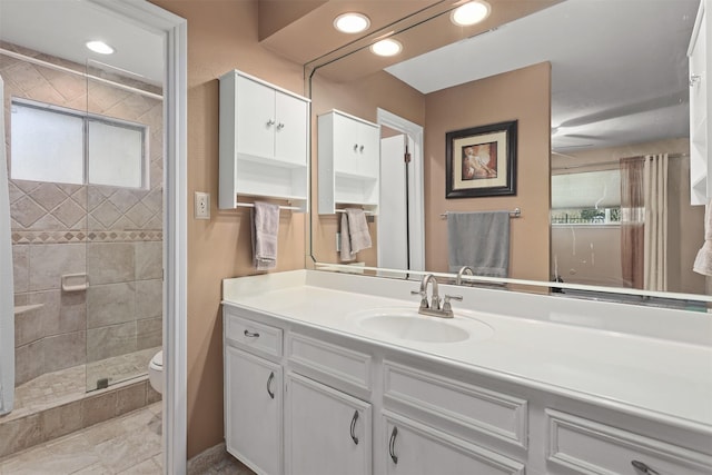 bathroom featuring vanity, a tile shower, a wealth of natural light, and toilet