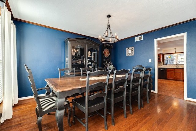 dining space featuring ornamental molding, dark hardwood / wood-style floors, a chandelier, and sink