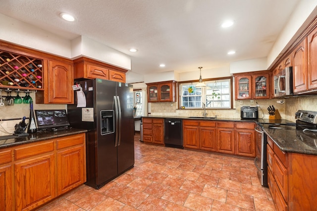 kitchen featuring pendant lighting, sink, dark stone countertops, backsplash, and black appliances