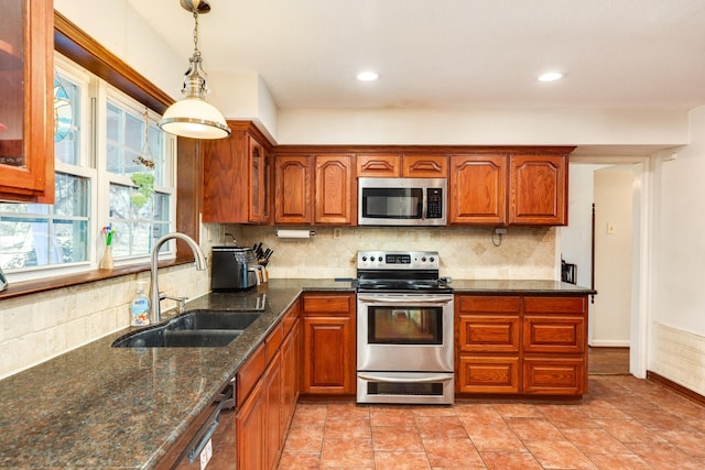 kitchen featuring sink, hanging light fixtures, dark stone countertops, stainless steel appliances, and backsplash