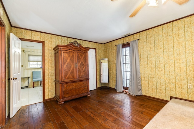 interior space with dark wood-type flooring, ornamental molding, and ceiling fan