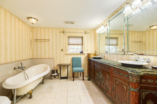 bathroom featuring vanity, plenty of natural light, a washtub, and tile patterned floors