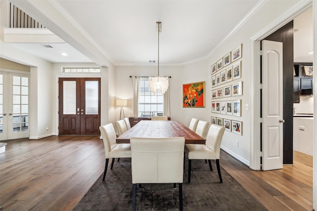 dining space with crown molding, dark wood-type flooring, french doors, and a chandelier