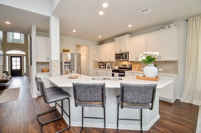 kitchen featuring white cabinetry, stainless steel appliances, and a kitchen island with sink