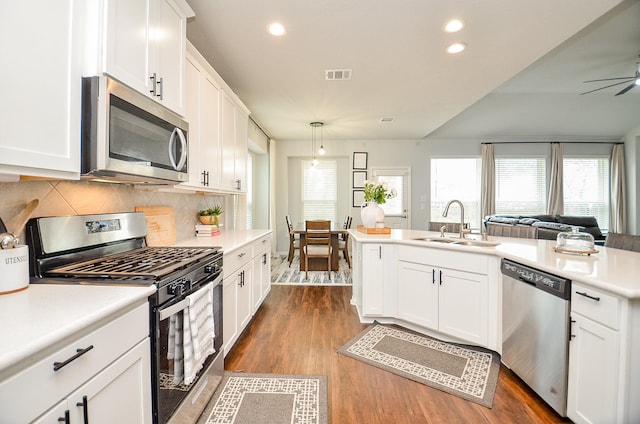 kitchen with sink, dark wood-type flooring, appliances with stainless steel finishes, white cabinetry, and hanging light fixtures