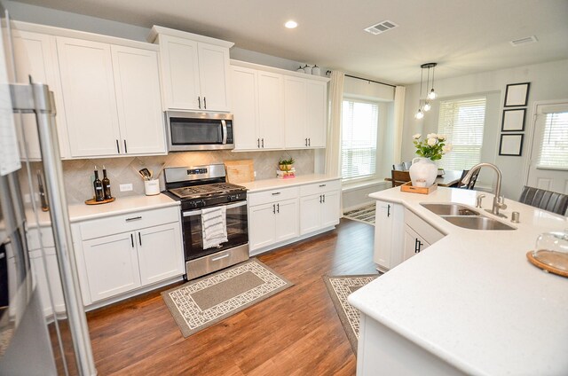 kitchen with white cabinetry, appliances with stainless steel finishes, sink, and decorative light fixtures