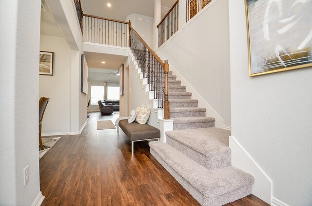 foyer featuring dark wood-type flooring, ceiling fan, and a towering ceiling