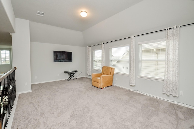 living area featuring light colored carpet, a healthy amount of sunlight, and vaulted ceiling