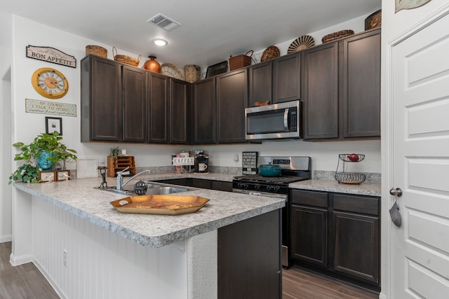 kitchen with sink, a breakfast bar, dark brown cabinets, stainless steel appliances, and kitchen peninsula