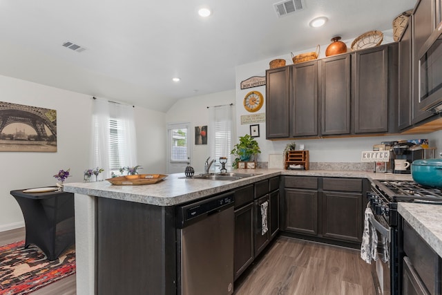 kitchen featuring lofted ceiling, sink, appliances with stainless steel finishes, hardwood / wood-style floors, and dark brown cabinets