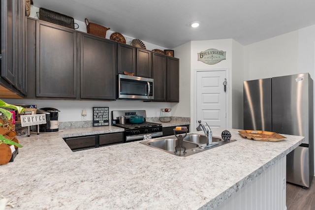 kitchen with wood-type flooring, appliances with stainless steel finishes, sink, and dark brown cabinetry