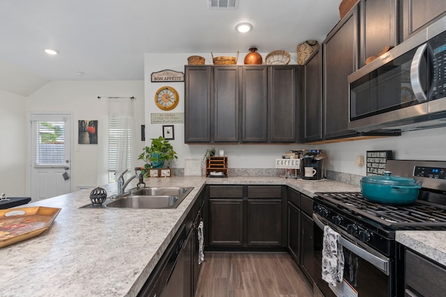 kitchen featuring appliances with stainless steel finishes, lofted ceiling, sink, light hardwood / wood-style floors, and dark brown cabinets