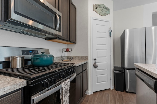 kitchen with stainless steel appliances, hardwood / wood-style floors, and dark brown cabinets