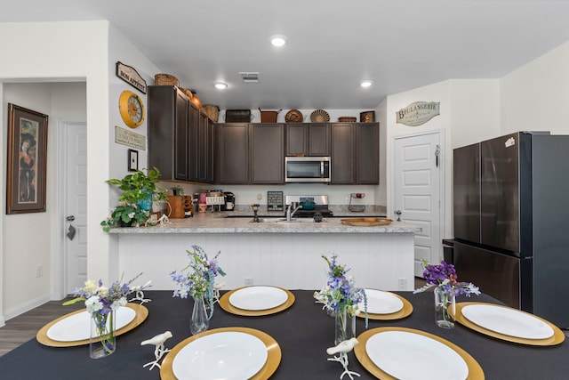 kitchen with sink, stainless steel appliances, dark hardwood / wood-style floors, dark brown cabinetry, and kitchen peninsula