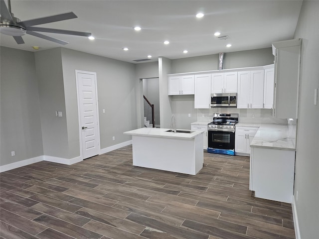 kitchen with sink, a center island with sink, appliances with stainless steel finishes, ceiling fan, and white cabinets