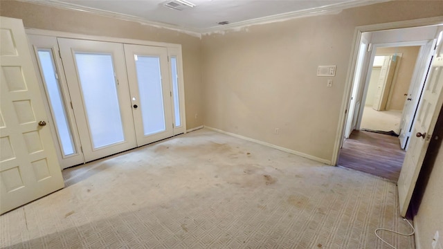 carpeted empty room featuring french doors and crown molding