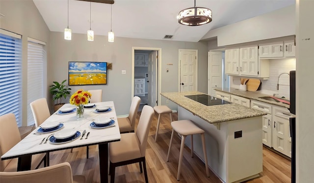 kitchen featuring hanging light fixtures, a center island, black electric stovetop, and decorative backsplash