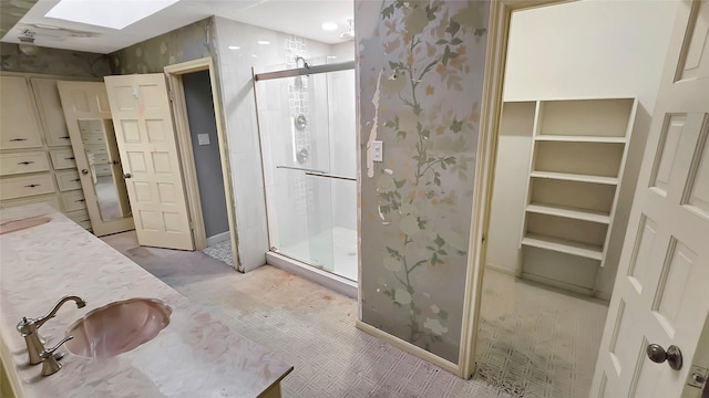 bathroom with vanity, an enclosed shower, and a skylight