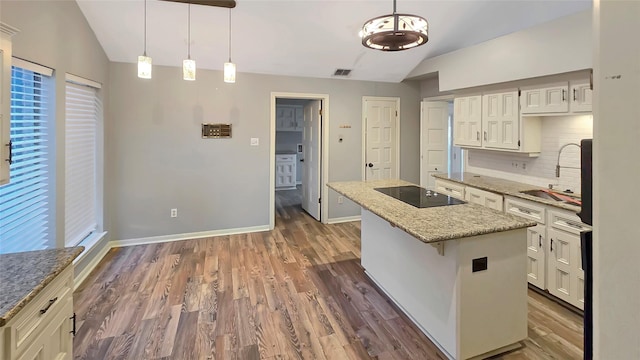 kitchen featuring sink, a kitchen island, pendant lighting, black electric stovetop, and backsplash