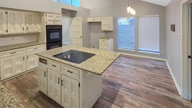 kitchen featuring lofted ceiling, dark hardwood / wood-style floors, black appliances, a kitchen island, and decorative light fixtures