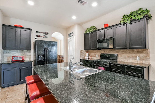 kitchen featuring tasteful backsplash, sink, black appliances, and an island with sink