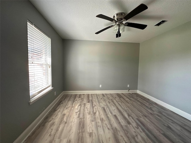 empty room featuring ceiling fan, hardwood / wood-style flooring, and a textured ceiling