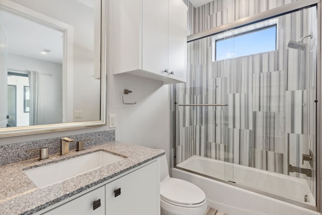 full bathroom with enclosed tub / shower combo, vanity, and toilet