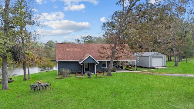 view of front of home featuring a carport, a front yard, a water view, a garage, and an outdoor structure