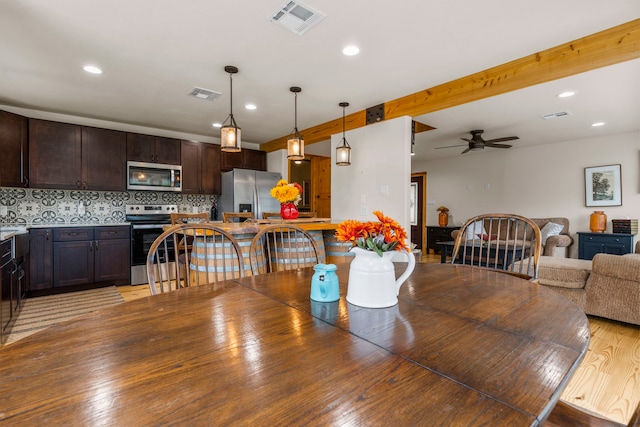 dining room featuring beamed ceiling, wood-type flooring, and ceiling fan