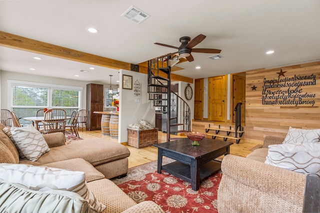 living room featuring beam ceiling, light hardwood / wood-style flooring, ceiling fan, and wood walls