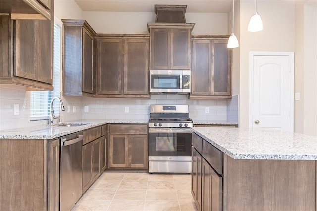 kitchen featuring pendant lighting, tasteful backsplash, light stone countertops, and appliances with stainless steel finishes