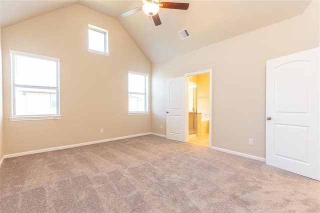 unfurnished bedroom featuring multiple windows, light carpet, connected bathroom, and ceiling fan