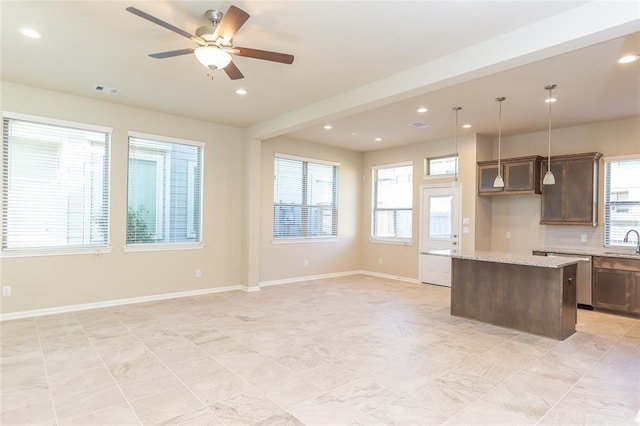 kitchen featuring sink, decorative light fixtures, a center island, dishwasher, and light stone countertops