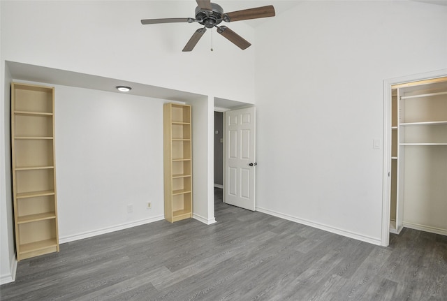 unfurnished bedroom featuring a walk in closet, dark hardwood / wood-style flooring, high vaulted ceiling, and ceiling fan