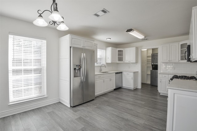 kitchen with sink, decorative light fixtures, appliances with stainless steel finishes, white cabinets, and backsplash