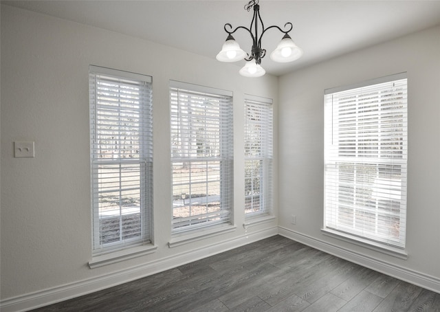 unfurnished dining area featuring an inviting chandelier and dark hardwood / wood-style flooring