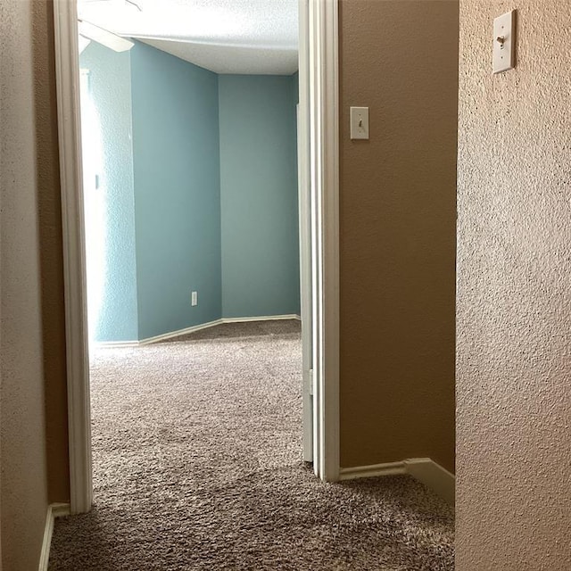 hallway featuring carpet and a textured ceiling