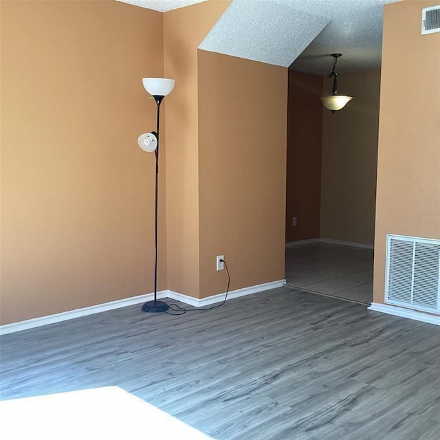 empty room with hardwood / wood-style flooring and a textured ceiling