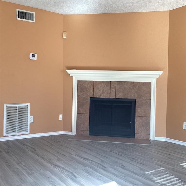 interior space with a tile fireplace, hardwood / wood-style floors, and a textured ceiling