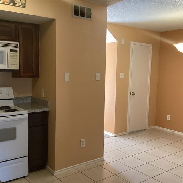 kitchen featuring light tile patterned floors, white appliances, dark brown cabinets, and a textured ceiling