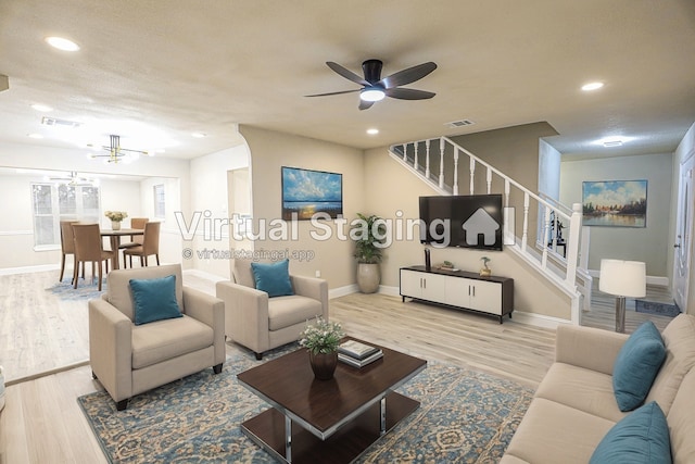 living room with ceiling fan, a textured ceiling, and light hardwood / wood-style floors