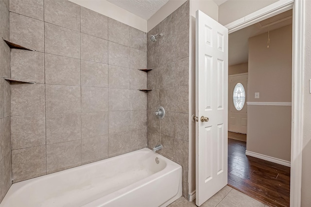 bathroom with tiled shower / bath combo, tile patterned flooring, and a textured ceiling