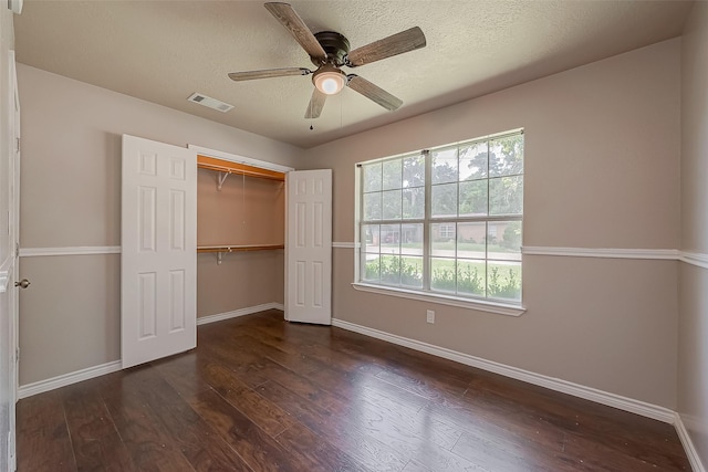 unfurnished bedroom featuring ceiling fan, dark hardwood / wood-style floors, a closet, and a textured ceiling