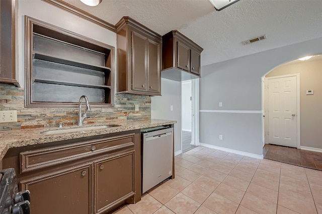 kitchen with sink, light stone counters, light tile patterned floors, dishwasher, and backsplash