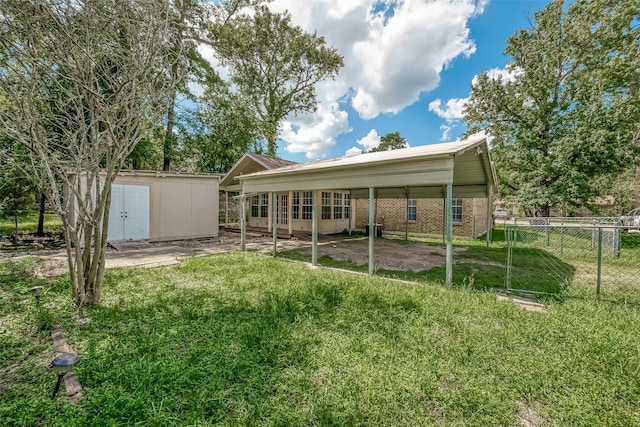 back of house with a lawn, a carport, and a storage unit